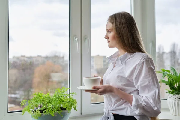 Retrato de mujer joven con taza de café cerca de la ventana de otoño de invierno — Foto de Stock