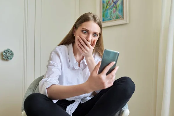 Emotionale junge schöne Frau blickt auf Smartphone-Bildschirm — Stockfoto