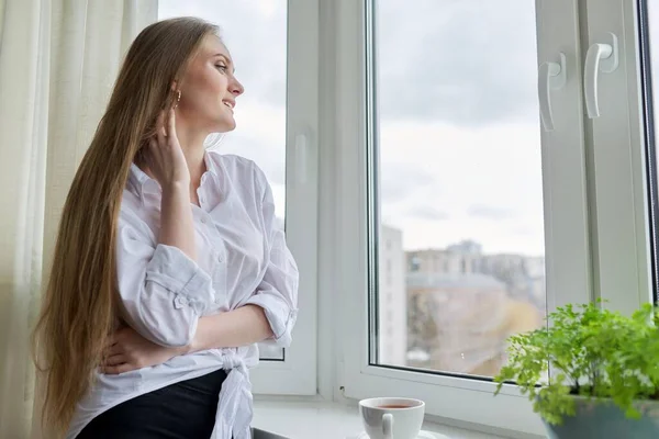 Retrato de mujer joven con taza de café cerca de la ventana de otoño de invierno — Foto de Stock