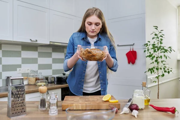Ung kvinna i hemmet kök matlagning kött, kyckling — Stockfoto