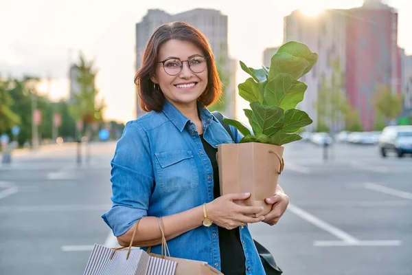 中年妇女带着纸袋，带着采购设备，看着相机 — 图库照片