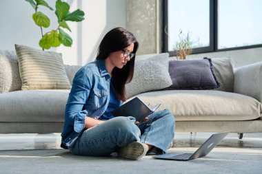 İş not defteriyle çalışan genç ve ciddi bir kadın evde oturuyor. Çalışmak için bilgisayar kullanan bir kadın serbest iletişim alışverişi blogculuk eğitimi alıyor. Teknolojik yaşam tarzı insanları