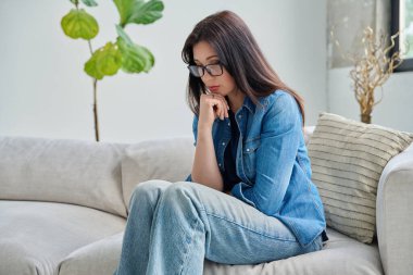 Evdeki kanepede oturan mutsuz genç kadın. Depresyon, stres, acı, sorunlar, akıl sağlığı insanları kavramı