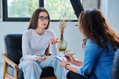 Üzgün, mutsuz kız öğrenci 17, 18, 19 yaşlarında profesyonel sosyal psikolog, terapist, danışman ile konuşuyor. Psikoloji, psikoterapi, akıl sağlığı, terapi, ergenlik konsepti.