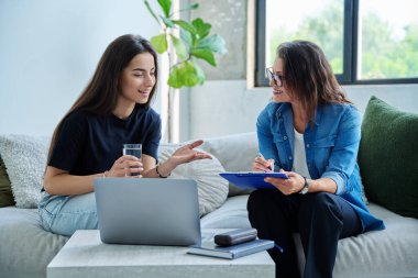 Terapi seansında genç gülümseyen kız hasta psikolog sosyal terapist ile birlikte kanepede oturuyor. Sağlık hizmeti gençlik yardımı, psikolojik hizmetler, psikoterapi
