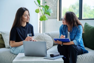 Terapi seansında genç gülümseyen kız hasta psikolog sosyal terapist ile birlikte kanepede oturuyor. Sağlık hizmeti gençlik yardımı, psikolojik hizmetler, psikoterapi