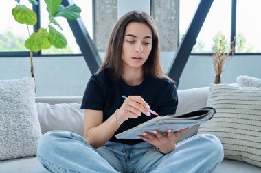 İnternet üzerinden ders kitabı okuyan genç üniversite öğrencisinin webcam görüntüsü, video dersi tavsiyesi, sohbet konferansı. Genç bayan blogger vlog kaydedici evde video kaydediliyor