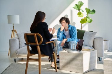 Akıl hastanesindeki genç adam profesyonel psikologla konuşuyor. Hasta ile çalışan kadın psikiyatrist danışmanı. Psikoloji psikiyatri tedavi desteği gençlere yardımcı oluyor