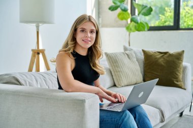 Genç bir kadının portresi kanepeye oturmuş iç dizüstü bilgisayarla kameraya bakıyor. Üniversite öğrencisi sınava hazırlanıyor, bilgisayar başında yazı yazıyor, rahatlıyor, sosyal medyayı okuyor.