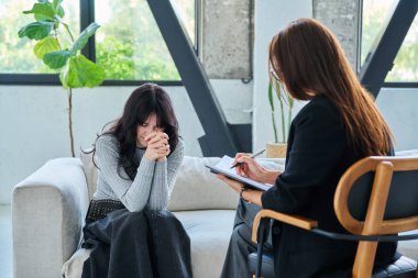 Üzgün, mutsuz, ciddi, genç bir kadın hastayı kadın terapist psikolog psikoterapist psikologla konuşurken strese sokuyor. Psikoloji psikoterapi tedavisi destek hizmetine yardımcı olur