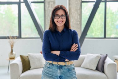 Ofiste kendine güvenen güzel bir kadının portresi. Kollarını kavuşturup kameraya bakan gülümseyen bir kadın. Güzellik, yaşam tarzı, sağlık, 30 'ların insan kavramı