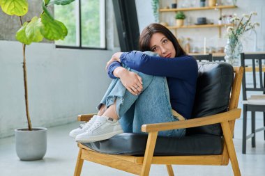 Oturma odasında sandalyede oturan güzel, mutlu, esmer kadının portresi. Kameraya bakan 30 'lu yaşlarda çekici bir kadın. Güzellik, yaşam tarzı, kadın konsepti