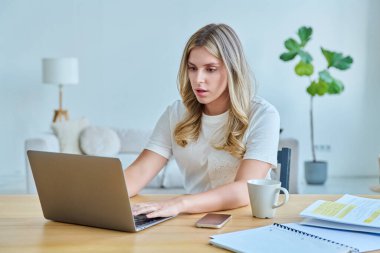 Masasında dizüstü bilgisayarlı ders kitaplarıyla oturan genç bir üniversite öğrencisi. Daktilo yazan defterler. Eğitim, eğitim, bilgi, gençlik kavramı