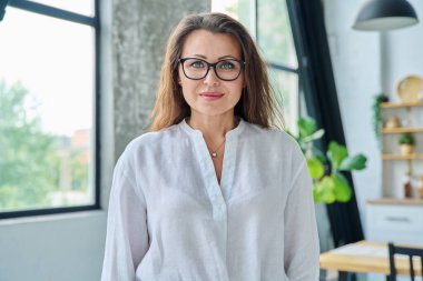 Headshot portrait of smiling confident elegant middle aged businesswoman with glasses in office. Beauty, business, career, success, work, mature age people concept