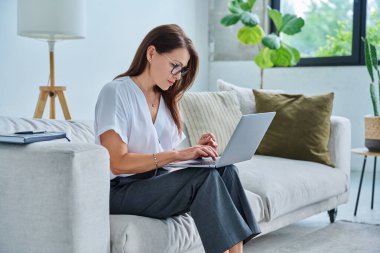 Merkez ofiste bilgisayarla çalışan orta yaşlı ciddi bir kadın, kanepede oturuyor. Kendine güvenen olgun bir kadın not alıyor, iş ödemeleri üzerine serbest meslek eğitimi alıyor.