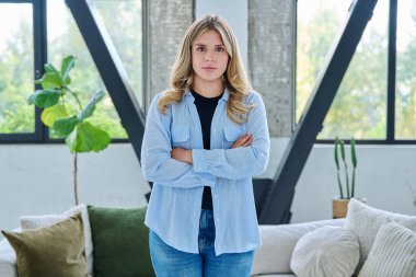 Evin içinde kendine güvenen gülümseyen genç bir kadının portresi. Kollarını kavuşturup kameraya bakan güzel, pozitif 20 'li yaşlarda bir kadın. Güzellik, gençlik, mutluluk, sağlık, yaşam tarzı konsepti