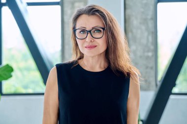 Ofisinde gözlüklü, zarif, orta yaşlı bir iş kadınının portresi. Güzellik, iş, kariyer, başarı, iş, olgun yaş insanları kavramı