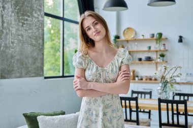 18-20 yaşlarındaki güzel sarışın bir kadının portresi ev içinde çapraz kollarla kameraya bakıyor. İnsanlar, gençlik yaşı, güzellik, sağlık, yaşam tarzı kavramı