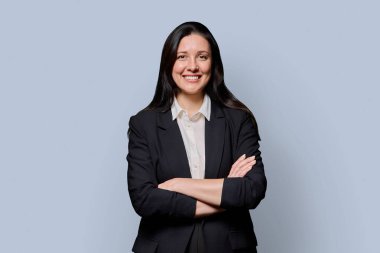 Gri stüdyo geçmişinde siyah ceketli başarılı orta yaşlı iş kadını. Kollarını kavuşturup kameraya bakan zarif, gülümseyen kadın. İşletme işi taşıyıcı yönetim çalışanları