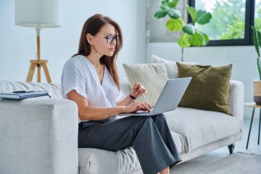 Merkez ofiste bilgisayarla çalışan orta yaşlı ciddi bir kadın, kanepede oturuyor. Kendine güvenen olgun bir kadın not alıyor, iş ödemeleri üzerine serbest meslek eğitimi alıyor.