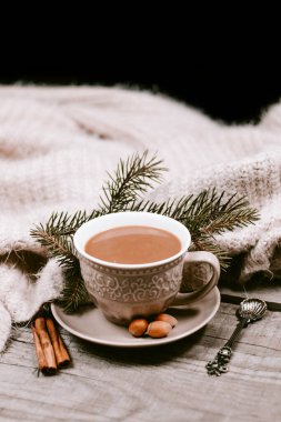 Sıcak kahve fincanı ahşap bir masada sıcak bir battaniyeye sarılı.