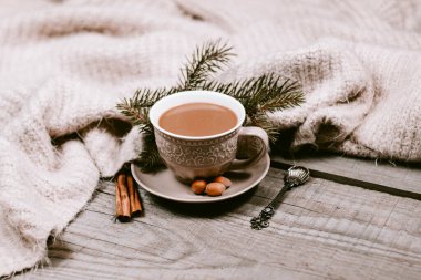 Sıcak kahve fincanı ahşap bir masada sıcak bir battaniyeye sarılı.