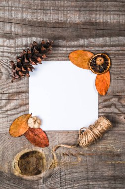 Tahta arka planda yapraklarla çevrili bir kağıt parçası.