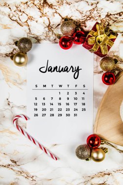Mermer zemin üzerinde boş bir kağıt parçası ve Ocak ayı takvimi ile kış tatili süslemeleri