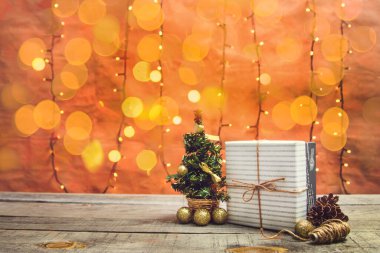 Noel süsleri ve ahşap bir masanın üzerinde bokeh ışıkları olan hediye kutusu.