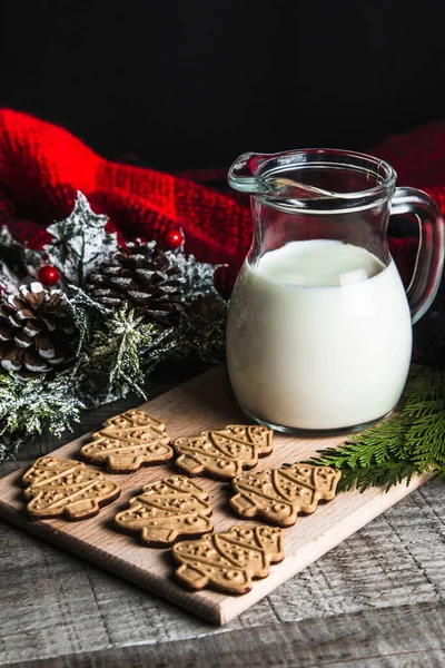 Taze süt ve Noel kurabiyeleri ve ahşap bir masada Noel süslemeleri.