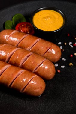 Siyah bir tabakta marul ve soslu ızgara sosis.