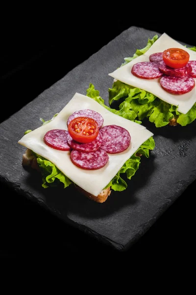 Frühstückssandwiches Mit Trockenfleisch Käse Und Salat Auf Einem Schwarzen Teller Stockfoto