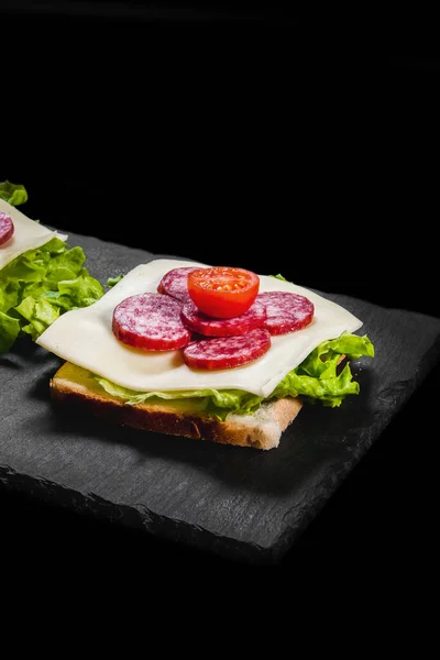 Frühstückssandwiches Mit Trockenfleisch Käse Und Salat Auf Einem Schwarzen Teller lizenzfreie Stockbilder