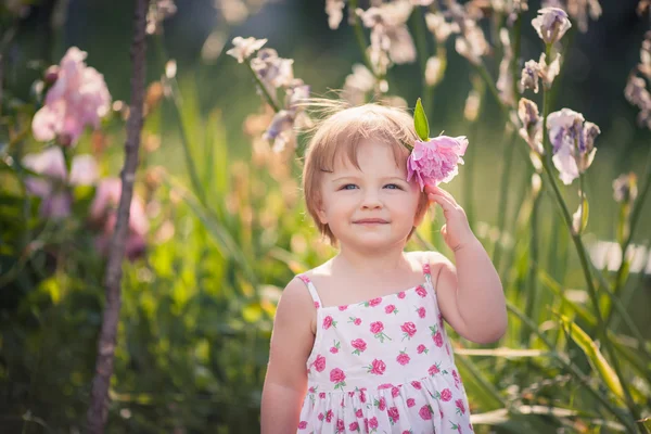 Baby girl in summer garden with bright flowers — Stock Photo, Image