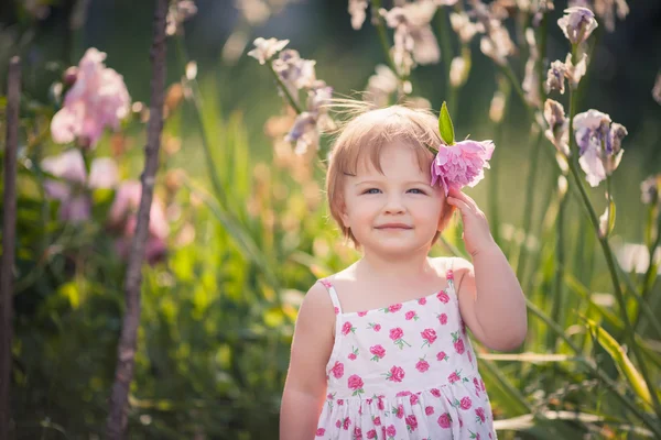 Baby girl in summer garden with bright flowers — Stock Photo, Image