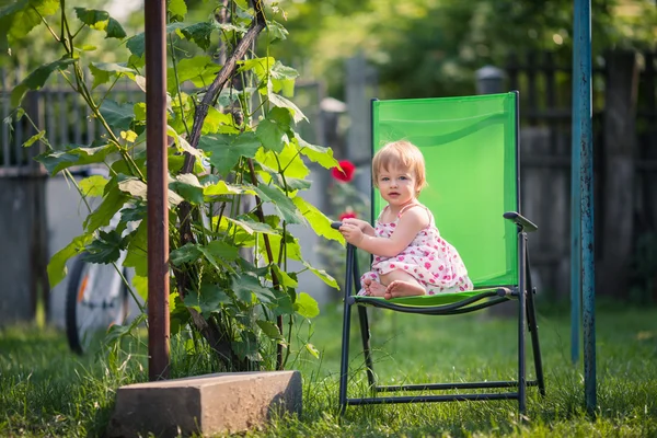 Bambina si siede sulla sedia da giardino vicino alla vite — Foto Stock