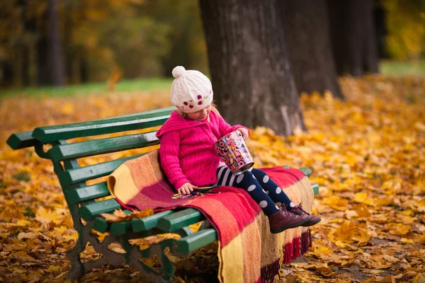 Little girl on the bench in the autumn garden — Stock Photo, Image