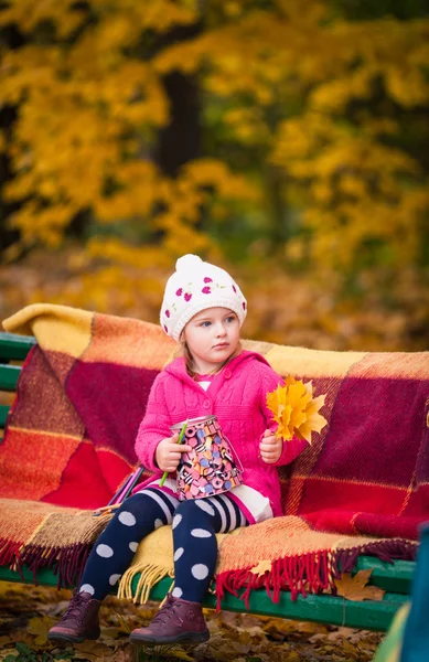 Little girl on the bench in the autumn garden — Stock Photo, Image