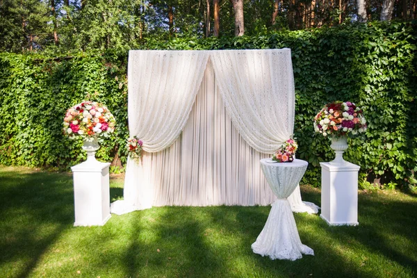 wedding arch with big flower bouquets on the green leaves backgr