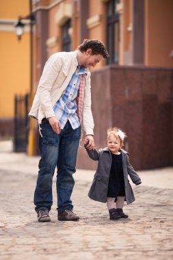 Babası kızının el sokakta tutar.