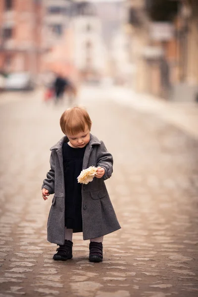 一个小宝贝女孩穿灰色大衣站在旧城的街道上 — 图库照片