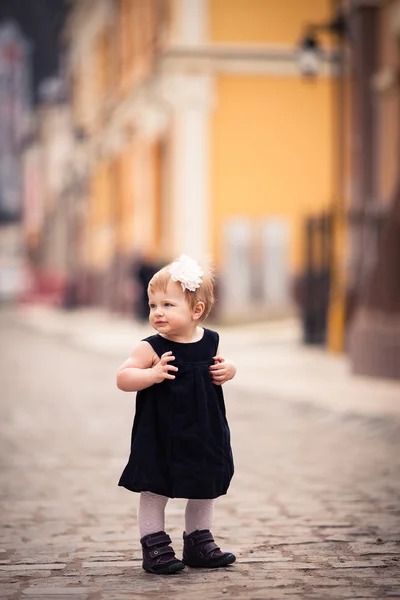 A little baby girl stands on the street — Stock Photo, Image