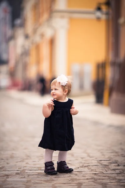 A little baby girl stands on the street — Stock Photo, Image