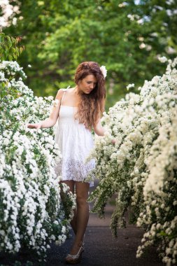 Çekici genç hanım standları tam uzunlukta bahar bahçe beyaz çiçek dolu