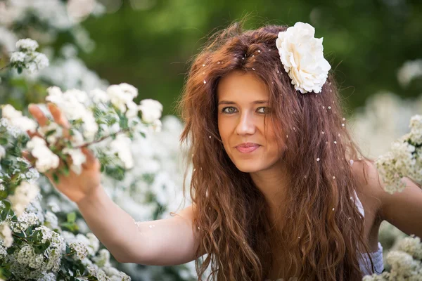 Retrato de encantadora jovem com belo sorriso no jardim da primavera cheio de flores brancas — Fotografia de Stock