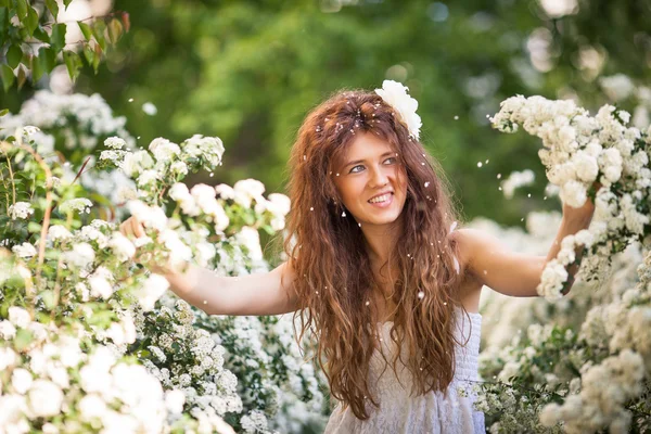 Vacker ung dam med charmiga leende våren trädgård full av vita blommor — Stockfoto