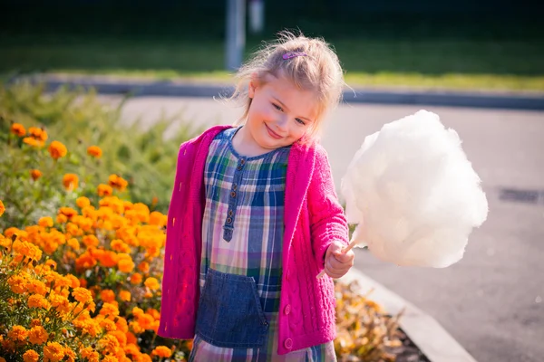 Sevimli küçük kız candyfloss ile parlak giysiler utangaç bir gülümseme ile