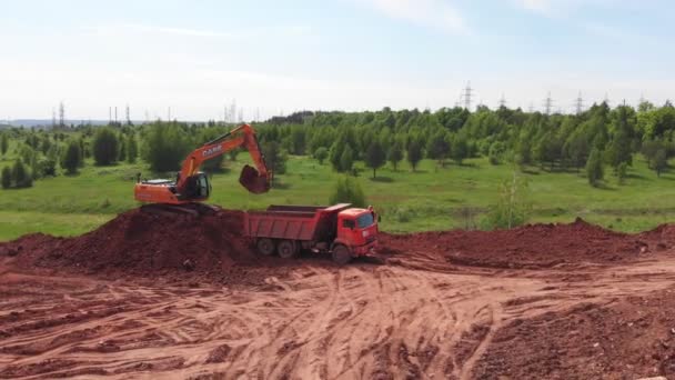 Az exkavátor talajt önt a billenős teherautó munkagépébe a dombon — Stock videók