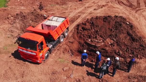 Trabajadores de pie cerca de trinchera y camión volquete cargado en el sitio — Vídeos de Stock