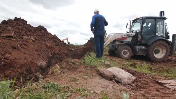 Trabajadores calificados controlan el entierro de trinchera con excavadora — Vídeos de Stock